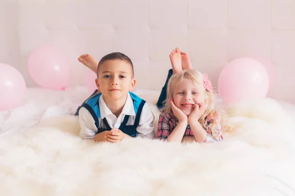 两个快乐的白人白种人可爱可爱有趣的孩子躺在卧室的床上的合影 男孩和女孩有乐趣与粉红色的气球 友谊和乐趣 永远最好的朋友 — 图库照片