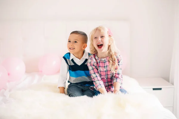 Portrait of two happy smiling laughing white Caucasian cute adorable funny children. Boy and girl hugging each other. Love, friendship and fun. Valentine day holiday celebration.