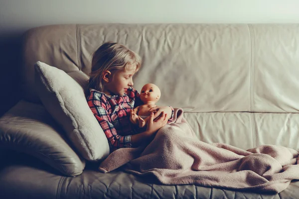 玩玩具的孩子 可爱的高加索女孩抱着娃娃 晚上的时候 孩子躺在室内的床上 与电影滤镜风格配合使用 快乐的童年生活方式 — 图库照片