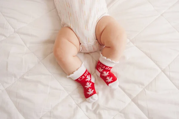 Nærme Hvite Lubne Babyføtter Iført Røde Sokker Med Kanadisk Lønneblad – stockfoto