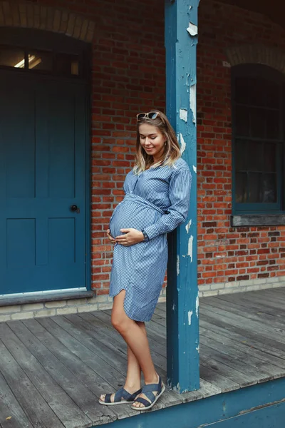 幸せな健康な妊娠 レンガ壁の建物の外に近いポーズ青色の長いドレスを着て妊娠中の若い白人女性の肖像画 フェミニンな期待の美女 — ストック写真