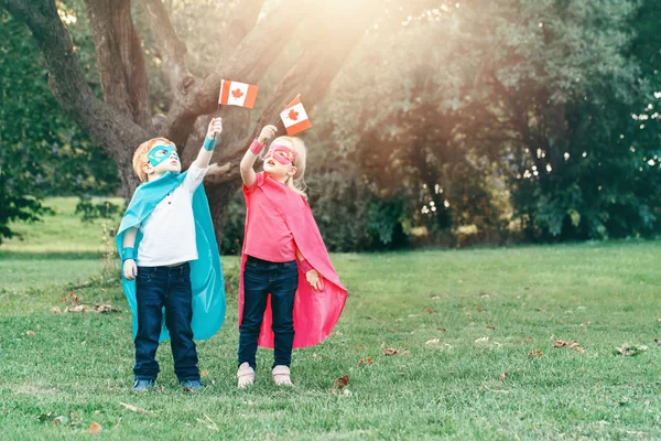 Kaukasiska Barn Superhjälte Cotumes Och Masker Håller Viftar Kanadensisk Flagga — Stockfoto