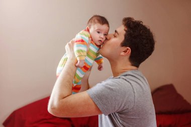 Beyaz bir baba yeni doğmuş bebeğe sarılıp öpüyor. Erkek, ebeveyn kucağında çocuk. Otantik yaşam tarzı dokunaklı bir an. Bekar baba aile hayatı konsepti. 