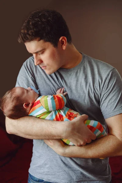 Young Caucasian father trying to calm down newborn baby. Male man parent holding rocking child on his hands. Authentic lifestyle documenatry moment. Single dad family life concept.