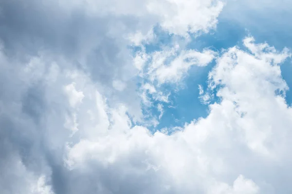 Dark blue sky with white grey clouds. Dramatic view of sun light beams coming from large big cumulus thunderclouds. Bad weather forecast.