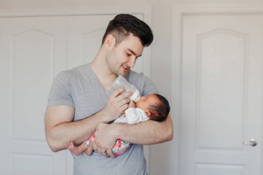Genç Kafkas baba baba Asya Çin karışık ırk yeni doğan bebek oğlu kızı şişeden süt ile besleme portresi. Otantik yaşam tarzı samimi gerçek an. Bekar baba aile hayatı kavramı.