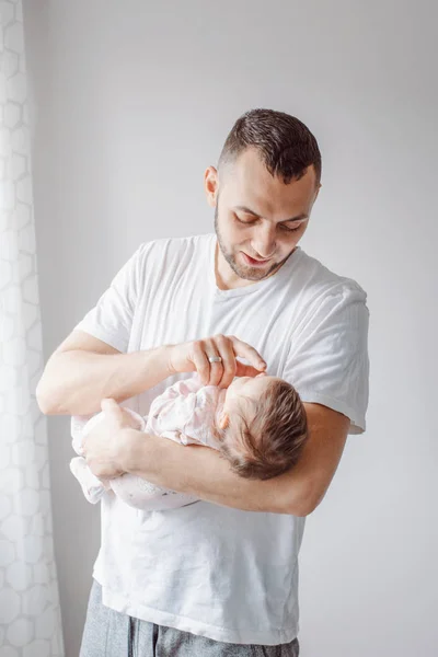 Young Caucasian father trying to calm down newborn baby. Male man parent holding rocking child on his hands. Authentic lifestyle documentary moment. Single dad family life concept.