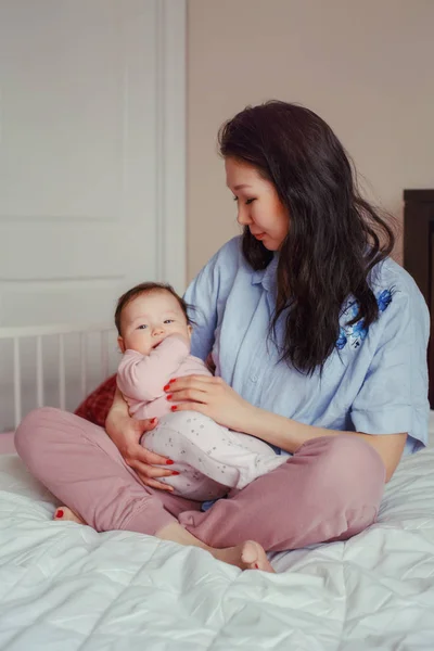 美丽的混血亚洲母亲的肖像抱着拥抱她可爱可爱的新生儿婴儿 早期发展和保健生活方式的概念 家庭在卧室 — 图库照片