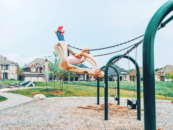 티셔츠와 청바지에 유치원 소녀는 놀이터 공기에 스윙에 라이프 스타일 개념입니다 — 스톡 사진