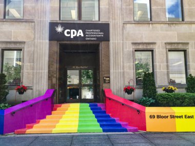 Toronto, Ontario, Canada - June 6, 2019: Toronto city getting ready to Pride Parade. Festive rainbow flag decoration on Toronto building of CPA (Chartered Professional Accountants). clipart