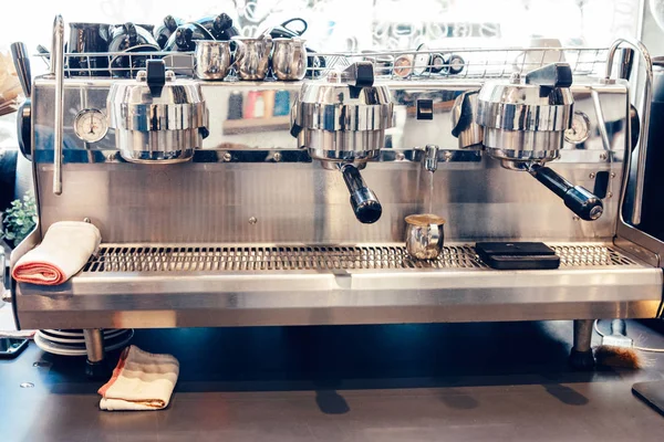 Professional coffee maker. Interior of food shop restaurant. Hot drink machine in cafe. Water running pouring to metallic cup jar. Clean flannel cotton towels lying on appliance.