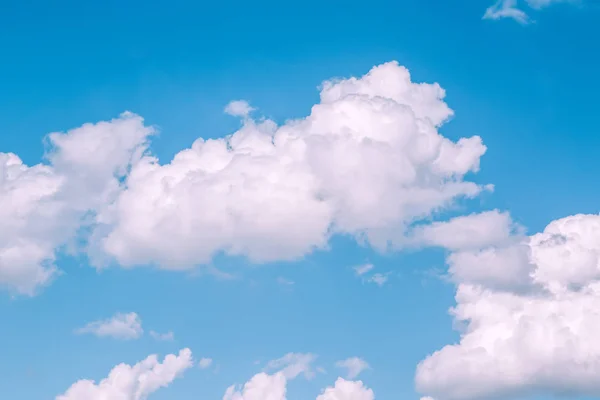 Light baby blue aquamarine sky with white pink clouds. Serene calm idyllic view of sun light coming from large big cumulus clouds. Toned with modern popular hipster style filters.