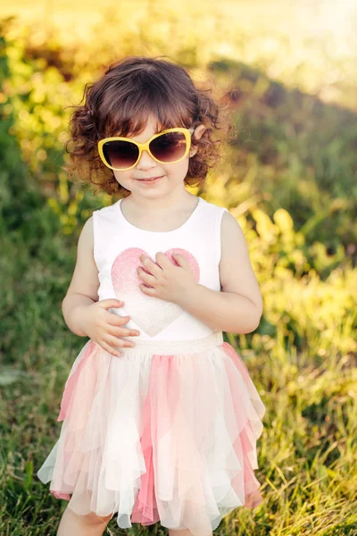 年轻的小女孩摆姿势 可爱的可爱的时尚白种儿童在粉红色礼服和黄色太阳镜在公园日落在夏天的肖像 小模型酷孩子有乐趣 — 图库照片