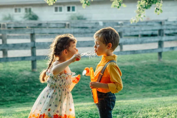夏の日没時に公園で石鹸の泡を吹く面白い白人の子供の女の子と男の子 友情の本物の本物の幸せな子供時代の瞬間 友人兄弟のライフスタイル活動 — ストック写真