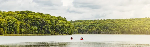 Canada forest park nature with family friends riding in red kayaks canoe boats in water. Beautiful landscape scene at Canadian  lake river area. Web banner header for website.