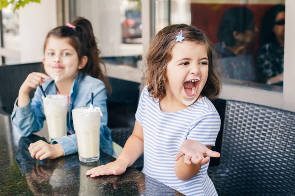 Two Funny Caucasian Little Preschool Sisters Siblings Drink Milk Shakes Stock Photo