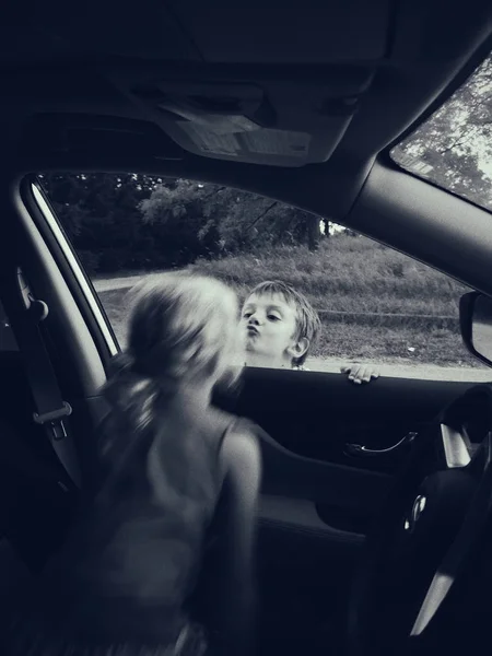 黑白直白的男孩和女孩通过开着的车窗接吻的肖像 朋友们互相道别 纯真真诚的孩子的爱和关系 运动动作模糊 — 图库照片