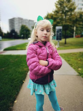 Kafasına kedi kulaklığı takan sevimli, sevimli, sevimli, sevimli, sevimli, beyaz, sarışın bir kızın portresi. Küçük çocuk sokakta poz veriyor.. 