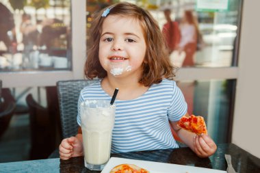 Kafeteryada milkshake içen Kafkas anaokulu çocuğu komik kız. Çocuk restoran avlusunda yemek içmekten zevk alıyor. Mutlu otantik çocukluk yaşam tarzı. 