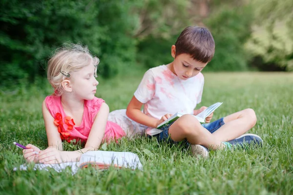 年轻的白人学校女生和男生朋友在户外公园做作业 孩子们读书 用铅笔写字 共同学习的儿童教育 — 图库照片