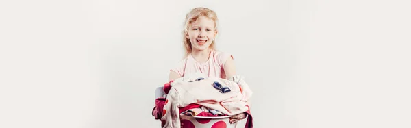 Mommy little helper. Smiling Caucasian girl child holding wash-basin with clothes and laundry detergent pods. Home chores housework for children. Web banner header for website.