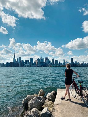 Bisikletli genç bir kadın Kanada 'nın Toronto şehrinin manzarasını seyrediyor. Modern büyük kasabada yaz sporu. Kanada Toronto adaları dönüm noktası. Güneşli gün doğası Ontario.