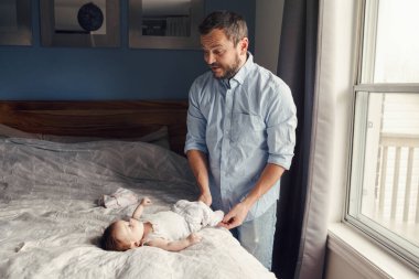 Orta yaşlı, beyaz bir baba, yeni doğan kız çocuğu için bebek bezi değiştiriyor. Erkek ebeveyn, çocuğuna evde bakıyor. Otantik yaşam tarzı samimi anı. Bekar baba aile gündüz hayatı. 