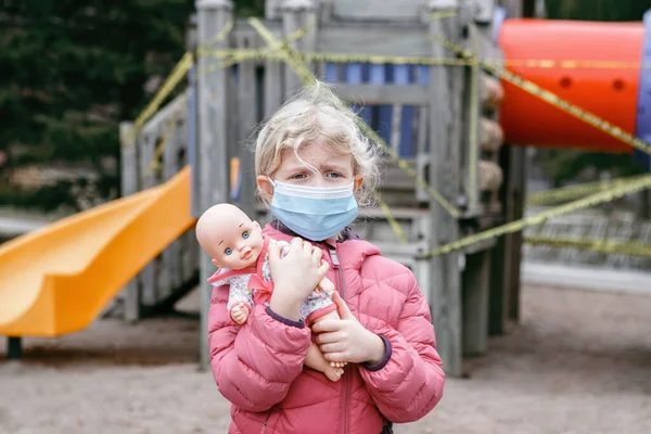 Szomorú Kaukázusi Lány Arcmaszkban Babajátékkal Zárt Játszótéren Szabadban Gyerekek Sárga — Stock Fotó