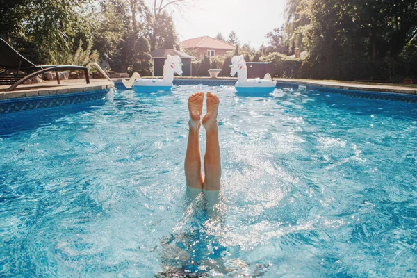 Funny child diving in swimming pool on home backyard. Kid child enjoying having fun in water. Summer outdoor water activity for kids. Legs up in the air in pool.