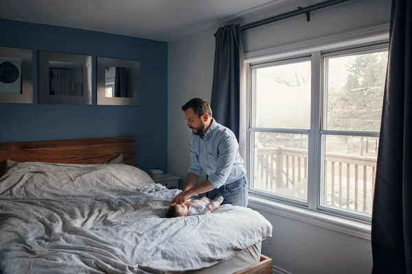 Middle age Caucasian father changing diaper clothes for newborn baby daughter son. Man parent taking care of child at home. Authentic lifestyle candid moment. Single dad family day life.