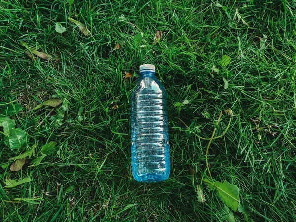 Plastic water bottle on ground in green grass. View from top above overhead. Ecological environmental world nature problem concept. Protection and saving of nature. Fresh water.