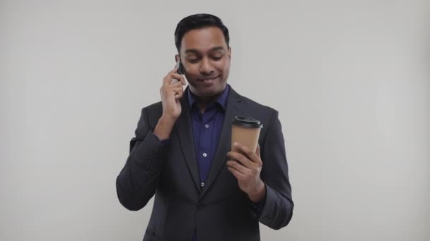 Бизнесмен разговаривает по телефону и пьет кофе изолирован. Индийский бизнесмен . — стоковое видео