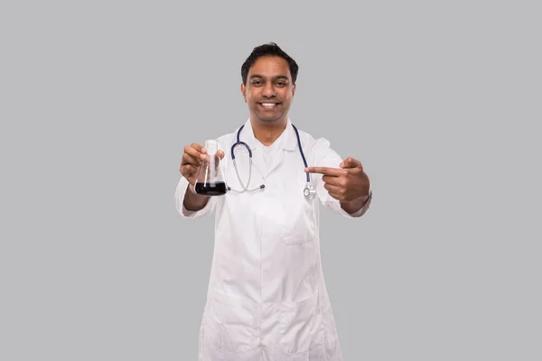 Muž Doktor ukazující na placatku s barevnou tekutinou izolovanou. Věda, medicína, virová koncepce. Indian Man Doctor Smilling. — Stock fotografie