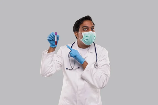 Arzt überrascht zeigt auf Blutrohranalyse und trägt medizinische Maske und Handschuhe. Indian Man Doktor Wissenschaft, medizinisches Konzept. Isoliert. — Stockfoto