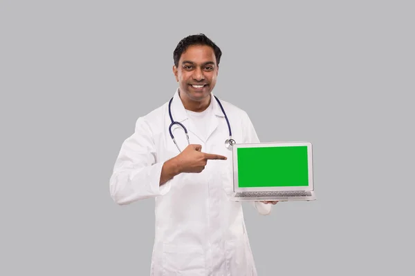 Arzt zeigt auf Laptop Green Screen Watching in Kamera isoliert. Indischer Arzt mit Laptop in der Hand. — Stockfoto