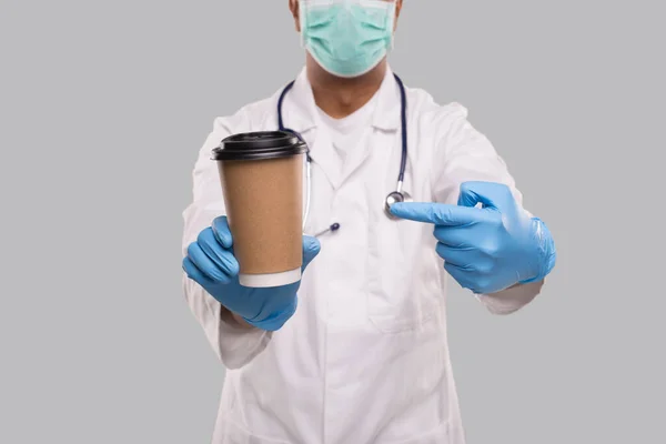 Indian Man Doctor Pointing bij Coffee Take Away Cup Het dragen van medische maskers en handschoenen close-up geïsoleerd. Indiase arts houdt koffie te gaan Cup. — Stockfoto