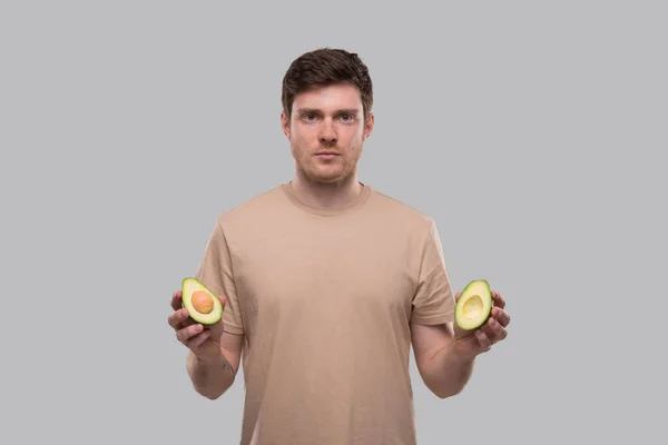 Man Holding Cut in Half Avocado geïsoleerd. Man Serieus gezicht. Geen Avocado, Stop Avocado Concept — Stockfoto