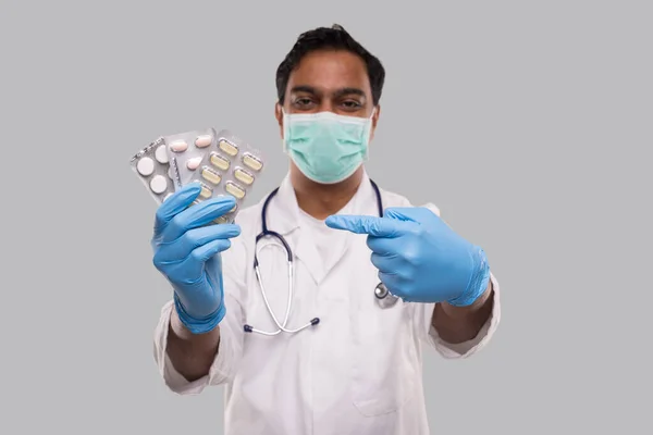 Man Doctor Apuntando a las Píldoras con Máscara Médica y Guantes. Doctor sosteniendo tabletas. indio hombre doctor aislado . — Foto de Stock