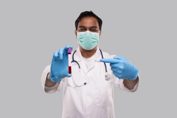 Indiase man die naar de bloedbuisanalyse wijst en medische maskers en handschoenen draagt. Wetenschap, medisch concept. geïsoleerd. — Stockfoto