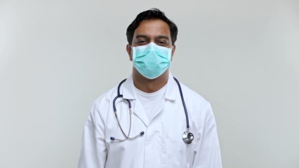 Lekarz zdejmujący maskę medyczną po pracy uśmiecha się. Indian Man Doctor izolowane Maska medyczna i rękawiczki. — Wideo stockowe