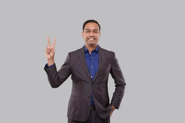 Geschäftsmann zeigt vereinzelt Friedenszeichen. Indischer Geschäftsmann steht lächelnd da — Stockfoto