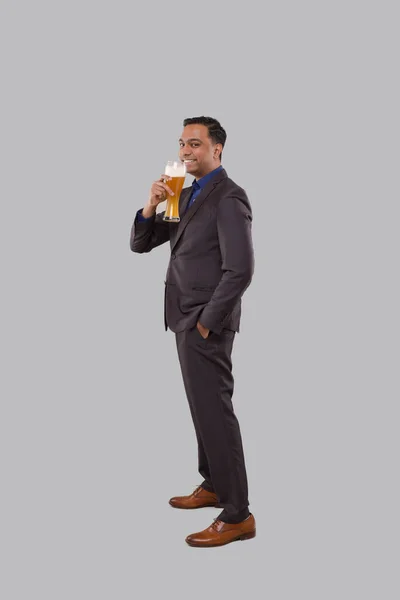 Zakenman drinkt bier uit Glass. Indiase zakenman staat volledige lengte met bier in de hand — Stockfoto