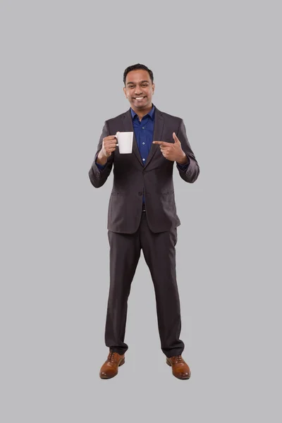 Empresário em pé apontando para a xícara de café. indiano empresário de pé comprimento total no terno com xícara de café — Fotografia de Stock