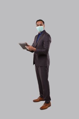 Tıbbi maske takan iş adamı tablet kullanılarak izole edildi. Hintli İş Adamı Elinde Tabletle Tam Uzunlukta Duruyor