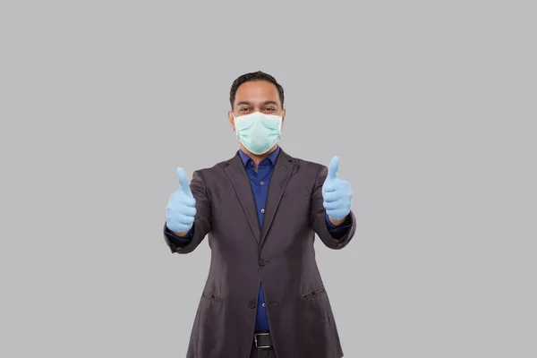Uomo d'affari che mostra Thump Up entrambe le mani che indossa maschera medica e guanti isolati. Indiano uomo d'affari in piedi Thump Up segno — Foto Stock