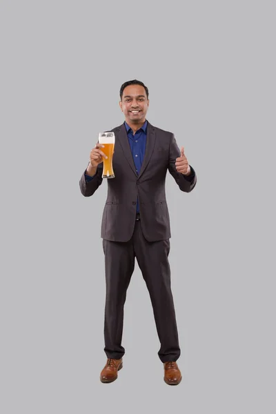 Zakenman die bierglas vasthoudt en duim laat zien. Indiase zakenman staat volledige lengte met bier in de hand — Stockfoto