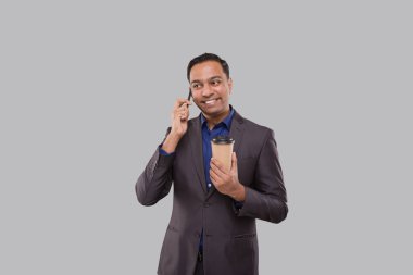 İş adamı telefonda kahve içip kupayı izole etmek için konuşuyor. Kahve kupası olan Hintli bir işadamı. Erkek