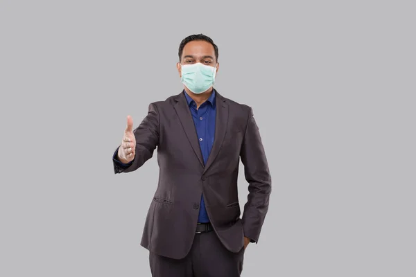 Indian Businessman offering hand to shake Wearing Medical Mask. Greeting and welcoming gesture. Business advertisement concept. Businessman Hand Shake. Man