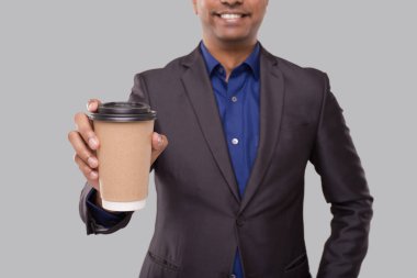 İş adamı, kahve bardağını kapalı tutuyor. Elinde kahve kupası olan Hintli bir işadamı. İç.