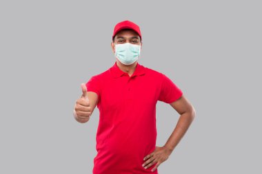 Teslimatçı Başparmağını kaldırdı. Tıbbi maske takıyor. Hintli Teslimatçı Çocuk gülümsüyor. Eve Teslimat. Erkek
